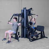 Man and woman using the chest press and overhead press stations together on the Body-Solid G9B Multi-Station Gym