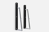 Two wall-mounted squat racks in black wood, one folded shut and one opened to a silver ladder